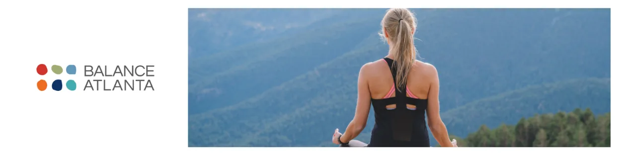 Person sitting cross-legged on a ledge facing mountains, meditating with an upright posture
