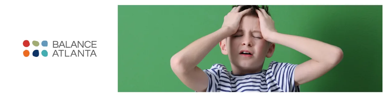 Child pressing hands to their temples and wincing in pain, on a green background with the Balance Atlanta logo at left.