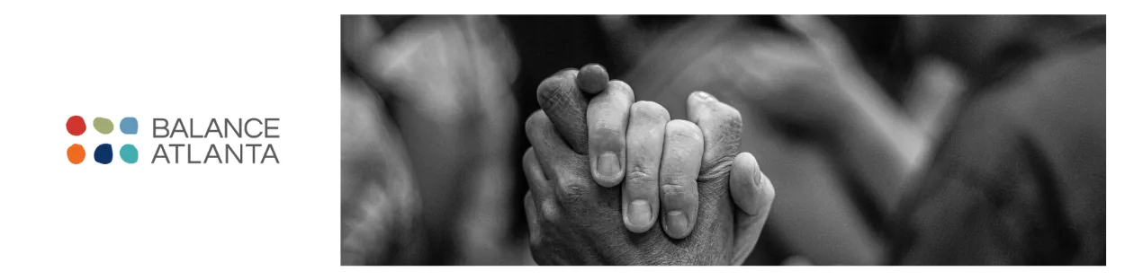 Black-and-white close-up of two hands clasped together beside the Balance Atlanta logo