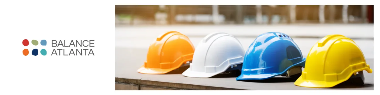 Four construction hard hats (orange, white, blue, yellow) lined up on a ledge with the Balance Atlanta logo at left