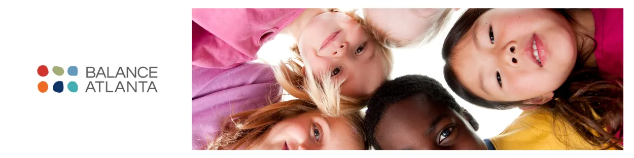 Group of children leaning heads together in a circle and smiling at the camera, with the Balance Atlanta logo to the left.