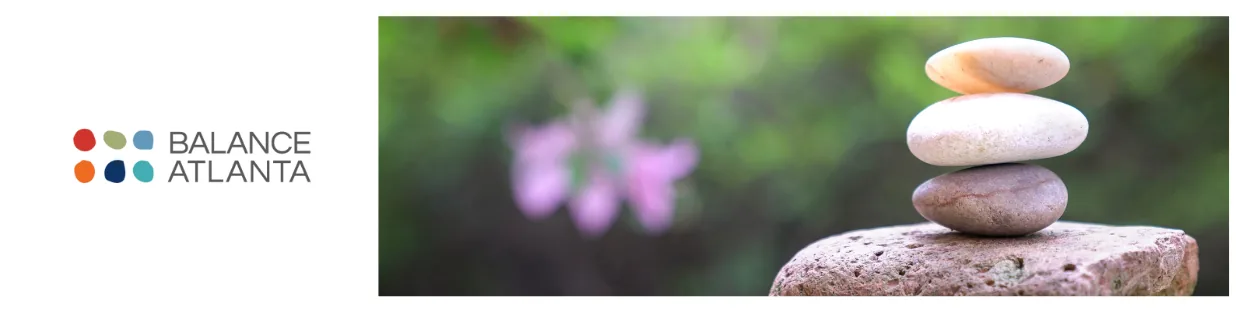Four smooth stones stacked on a rock with a blurred green background and pink flower bokeh, plus the Balance Atlanta logo on a white panel at left.