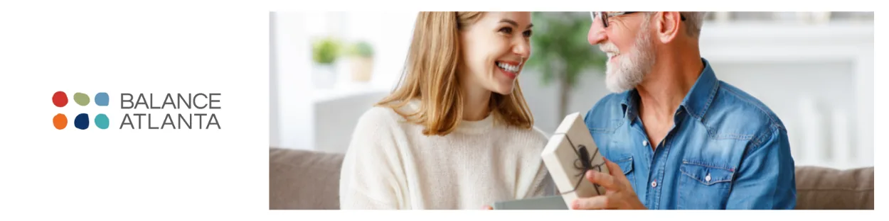 Balance Atlanta logo at left; a smiling woman hands a wrapped gift to an older man seated on a couch.
