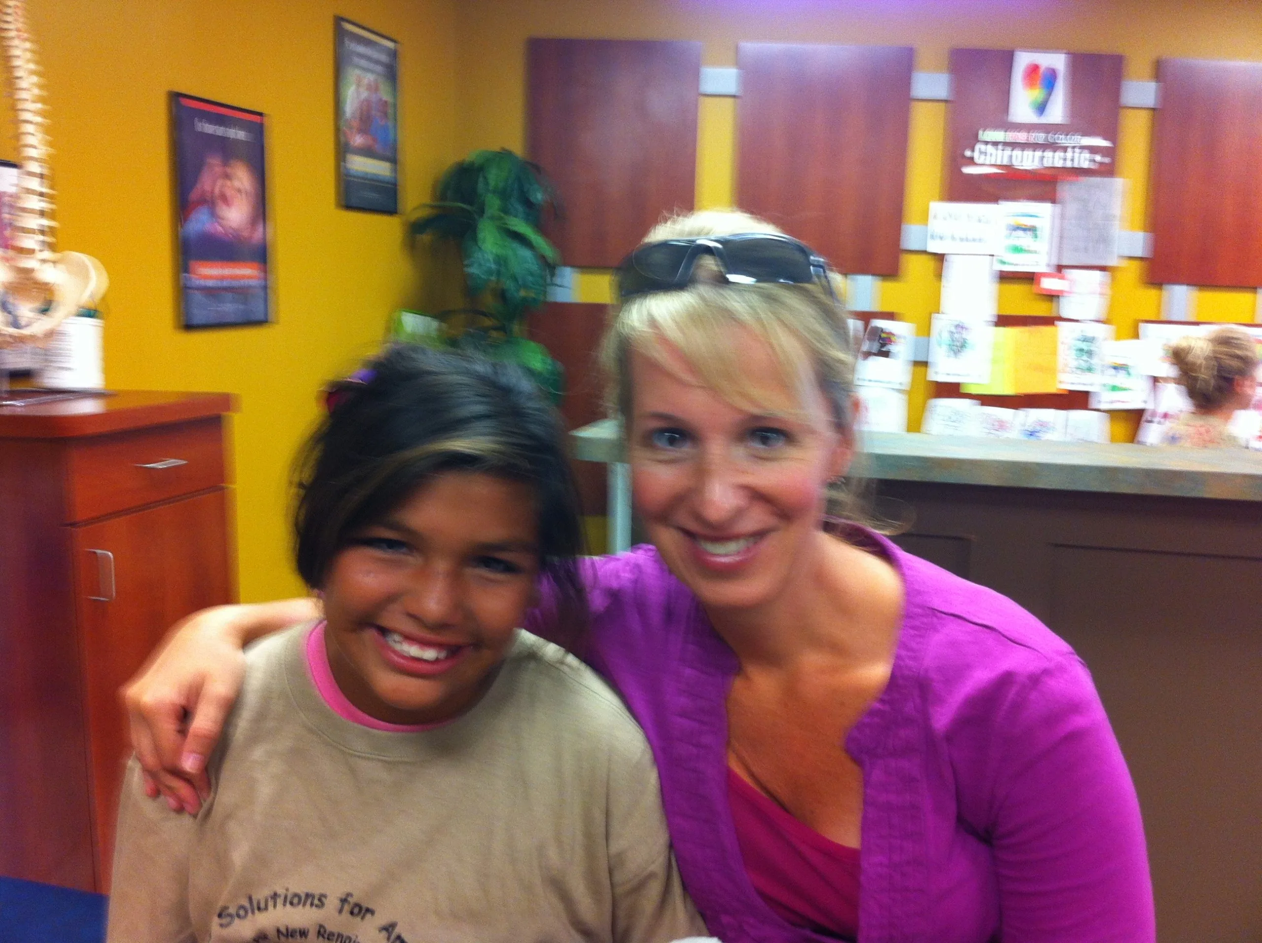 Adult and child smiling together in a bright clinic reception area