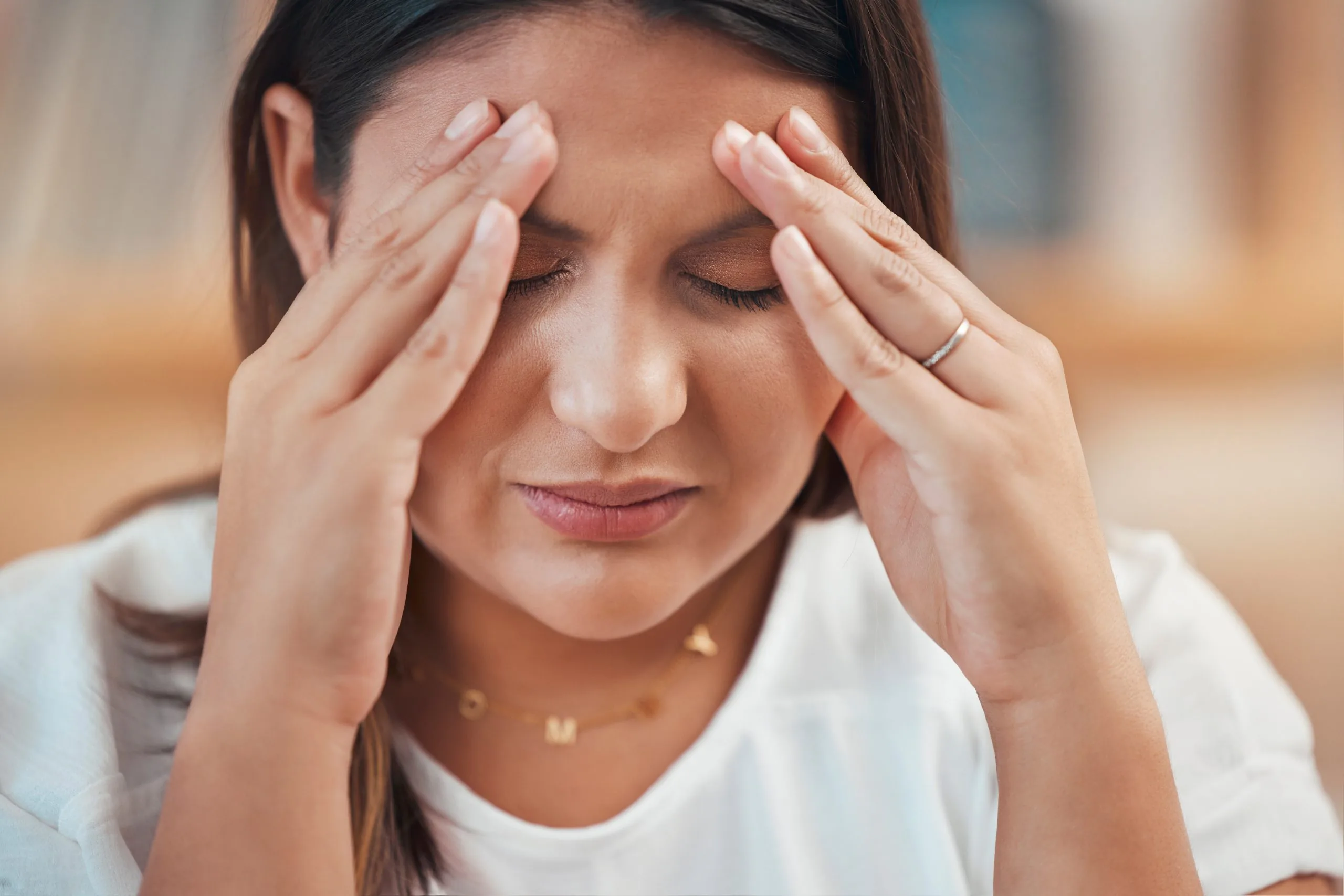 Person pressing their temples with both hands and eyes closed