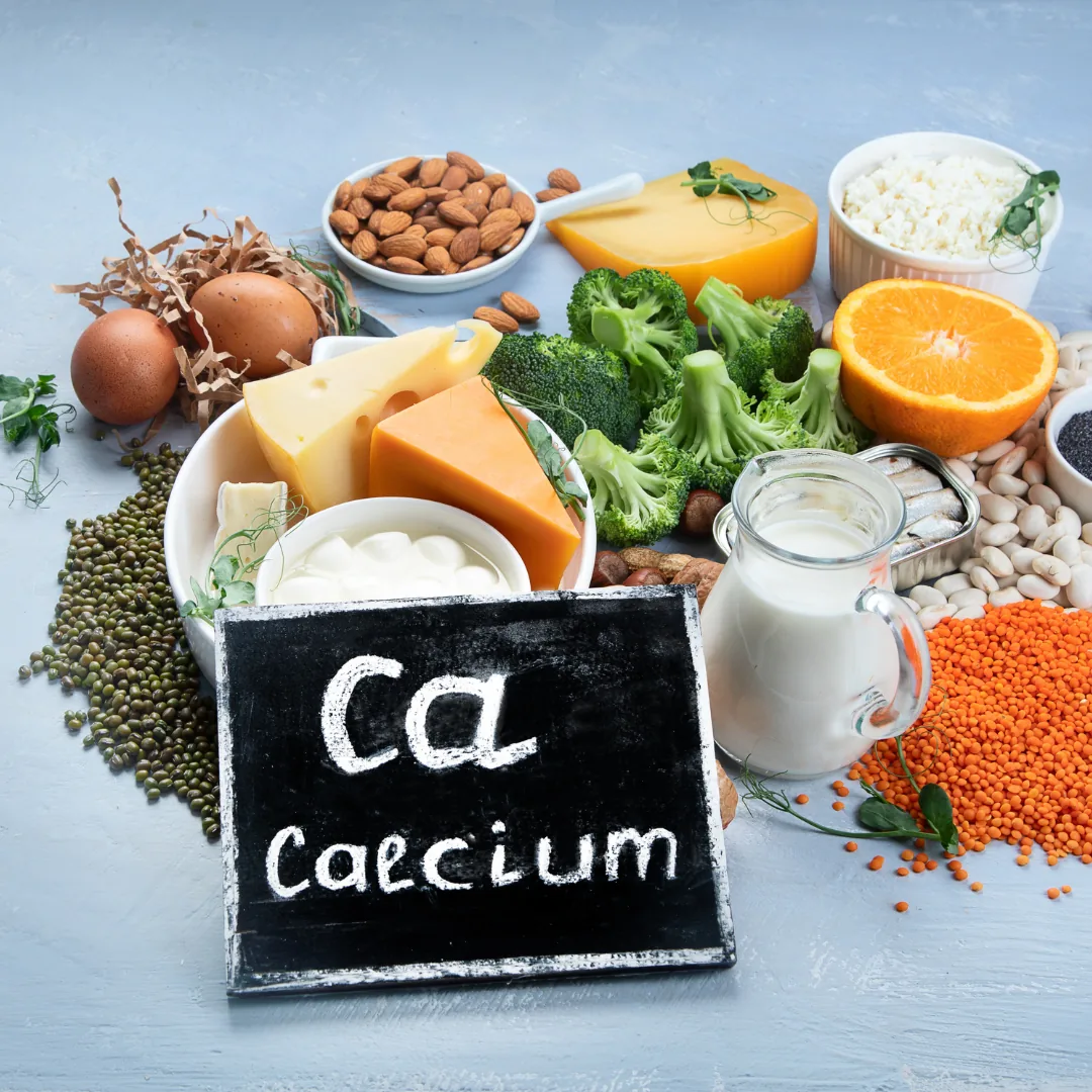 Chalkboard reading 'Ca calcium' surrounded by calcium-rich foods including cheese, milk, yogurt, broccoli, almonds, eggs and an orange.