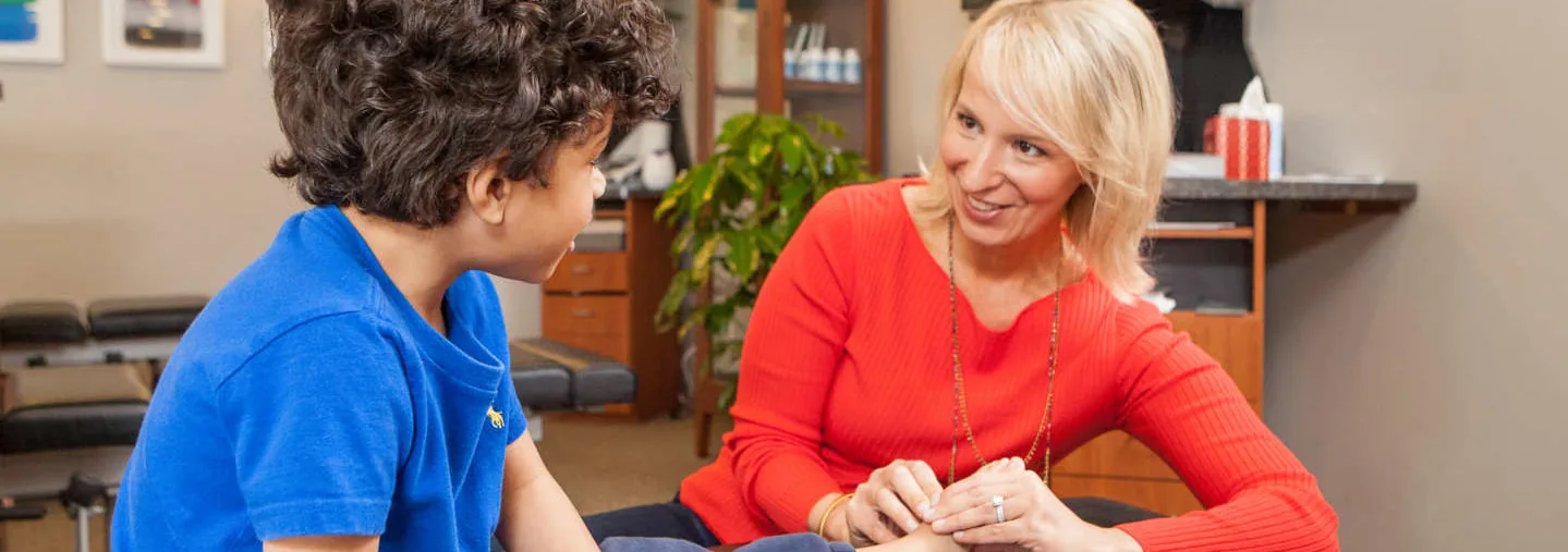 Clinician holding a patient's foot while talking with them in a chiropractic treatment room