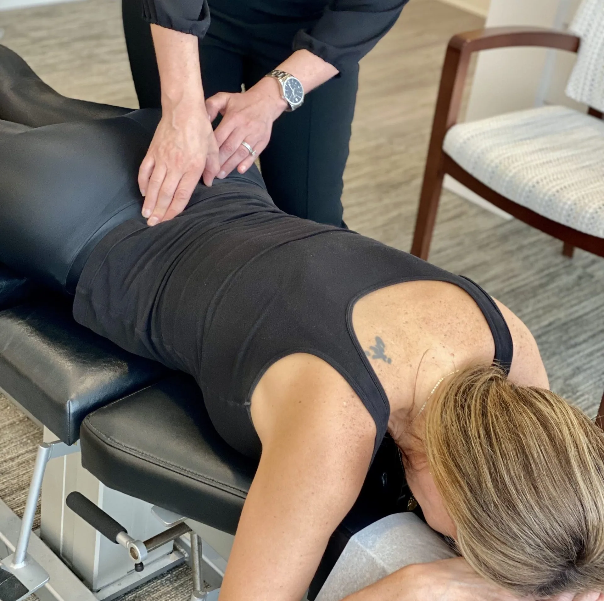 Practitioner applying a lumbar adjustment to a patient lying face down on a chiropractic treatment table.