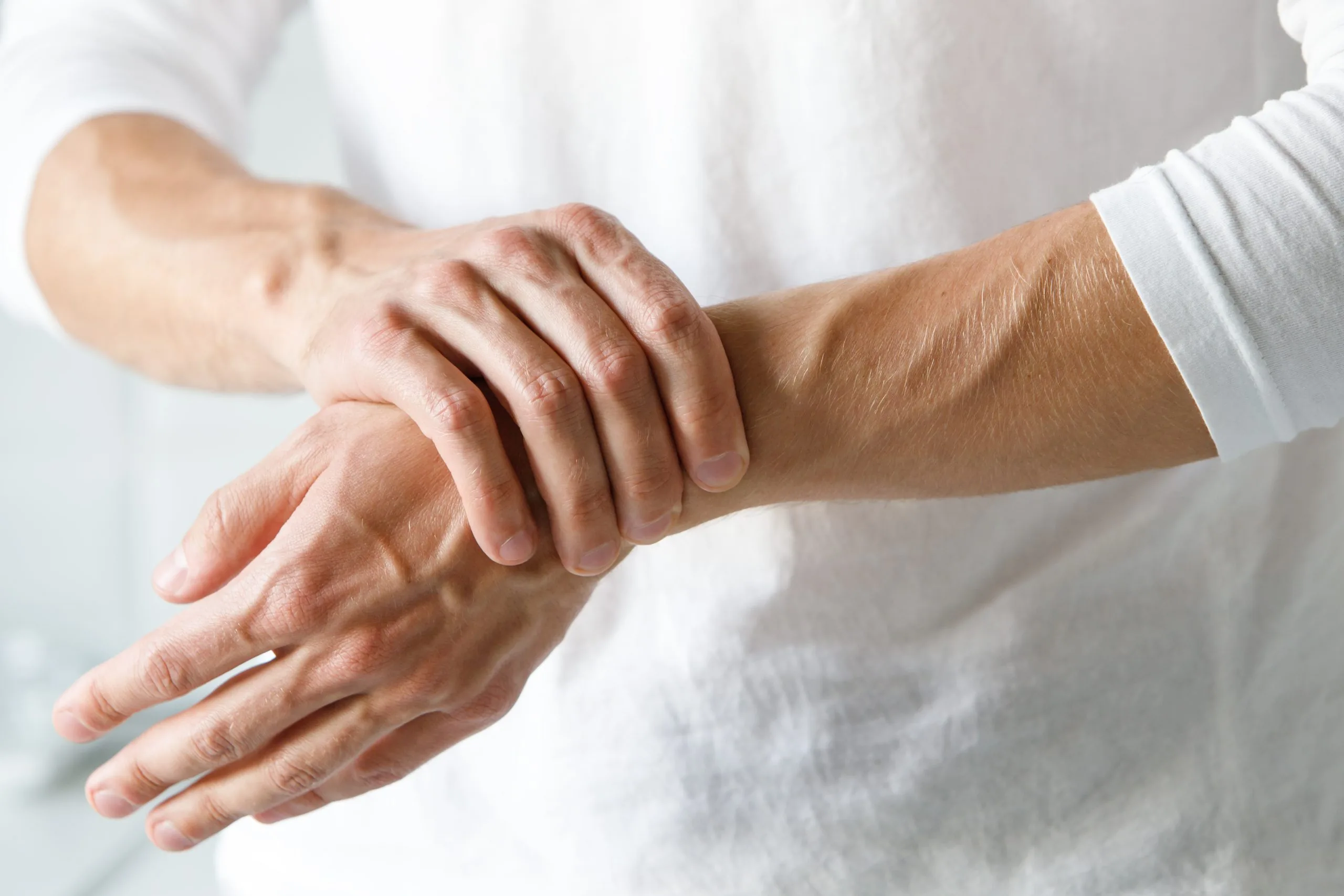 Person holding and pressing their wrist with the opposite hand, suggesting wrist pain or carpal tunnel discomfort.