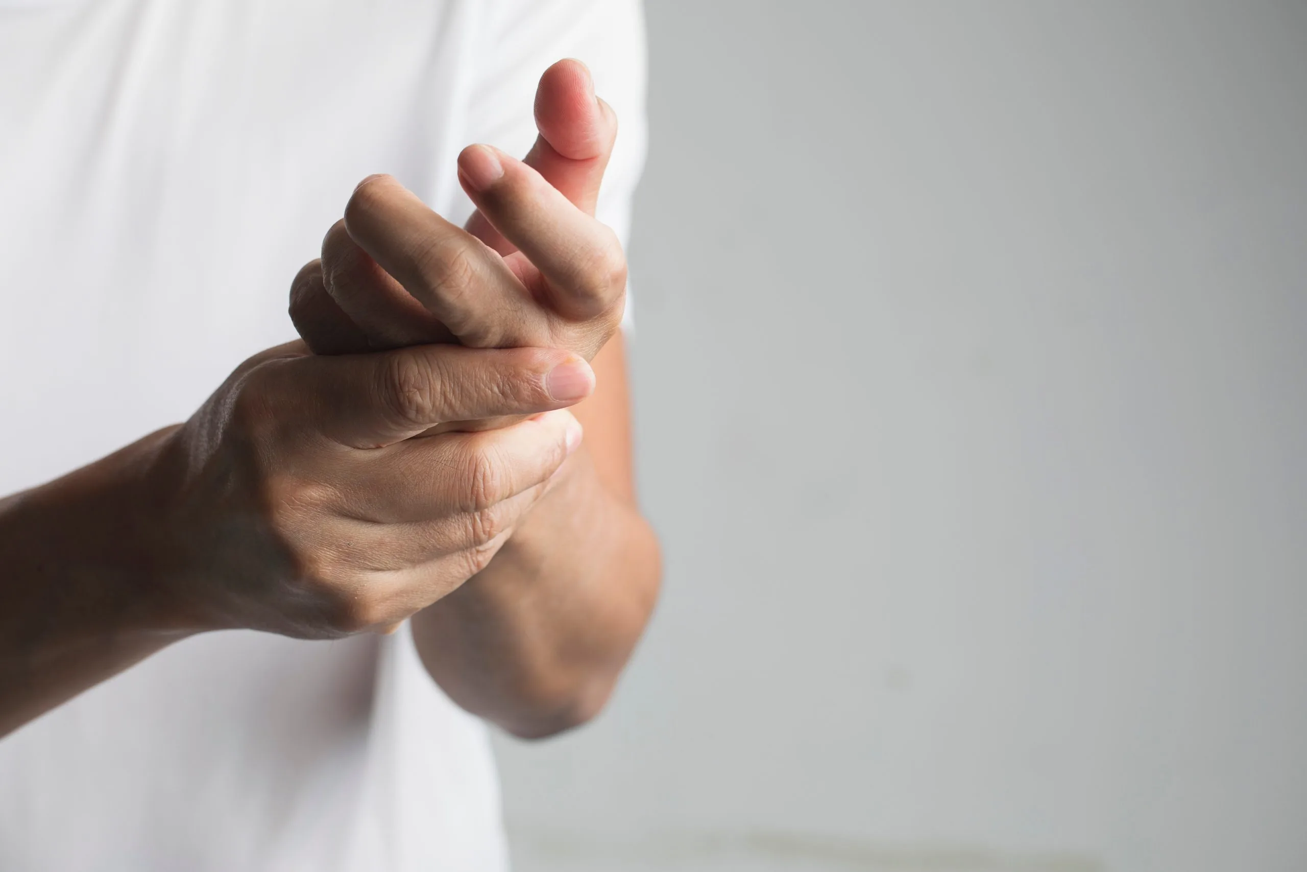 Close-up of hands clasping fingers and wrist, illustrating hand numbness or tingling associated with diabetic neuropathy