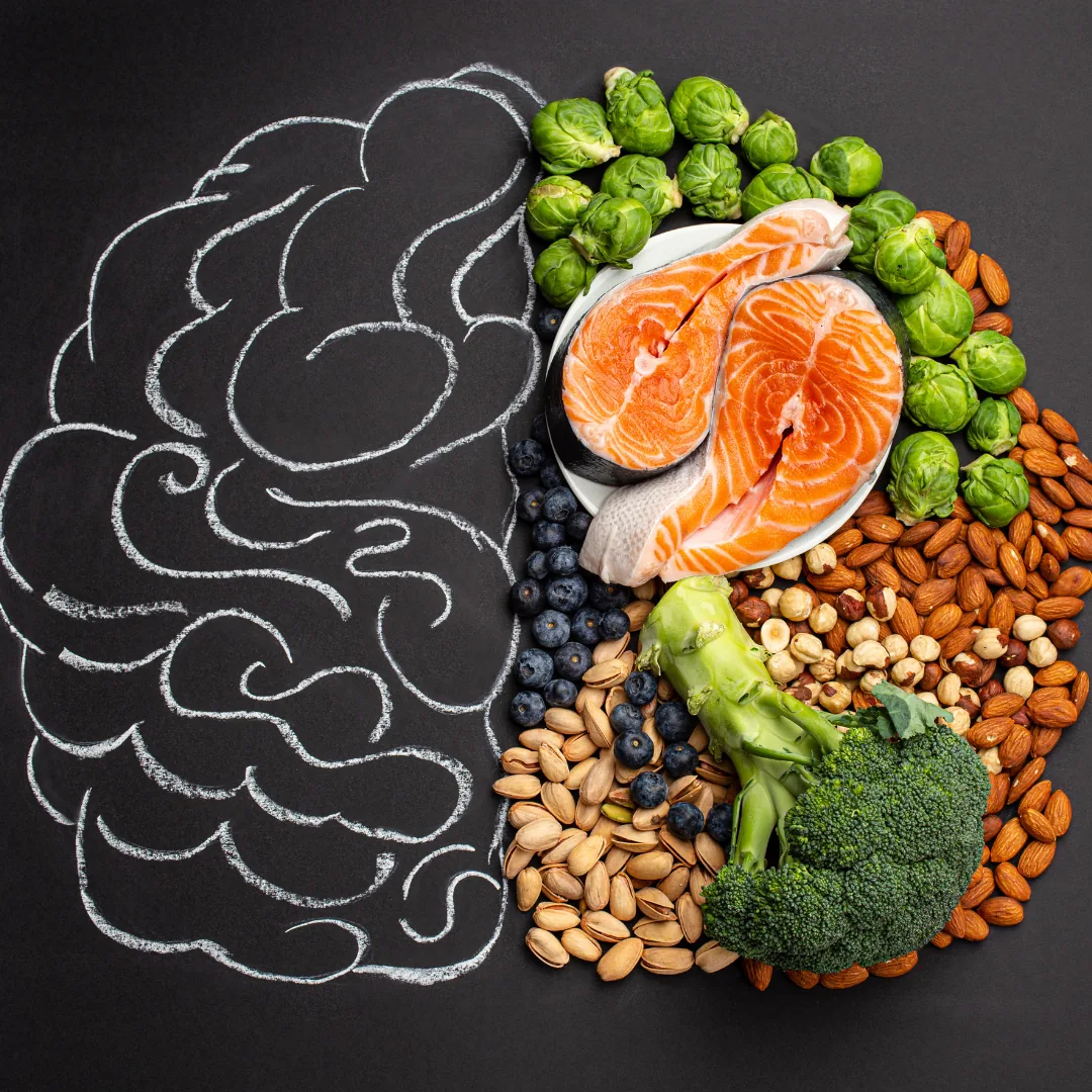 Chalk-drawn brain outline beside salmon, broccoli, nuts and berries arranged to represent brain-healthy nutrition.
