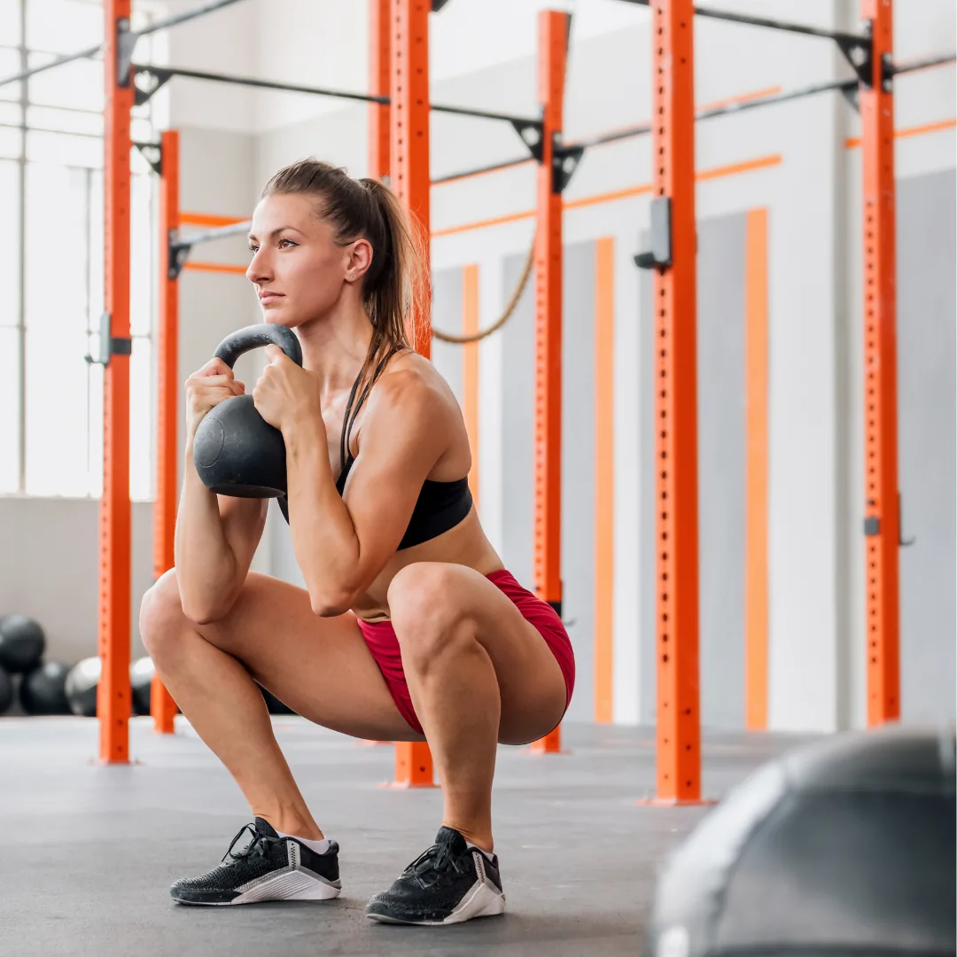 Woman performing a kettlebell goblet squat in a gym