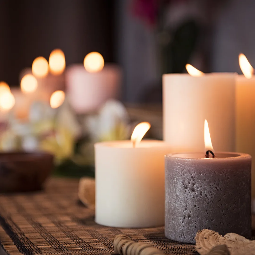 Several lit pillar candles on a woven mat creating a warm, calming ambience.