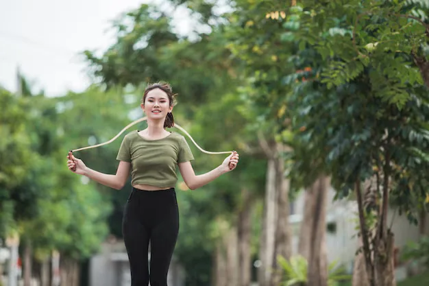 Woman jumping rope on a tree-lined path outdoors