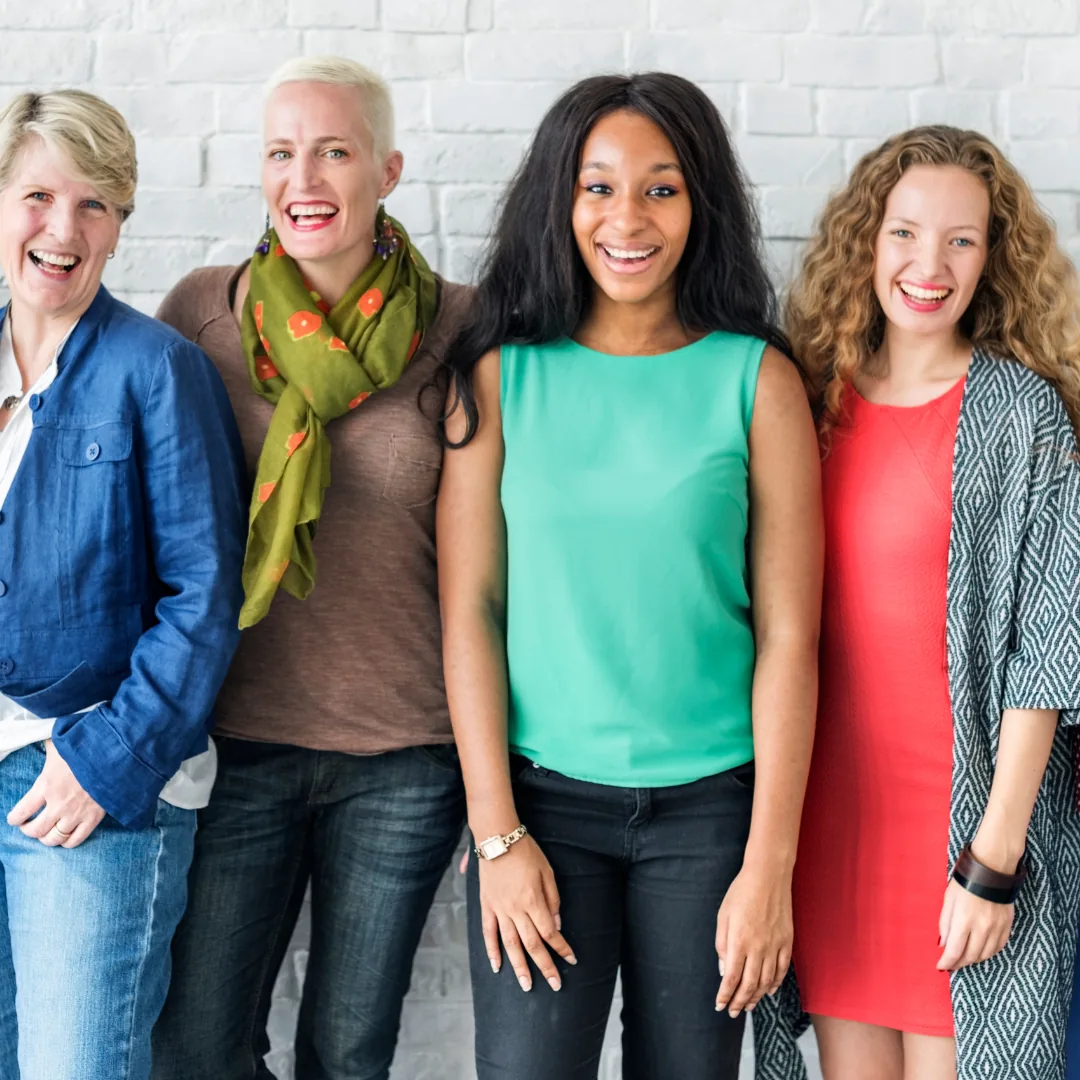 Four women standing close together and smiling, suggesting a supportive group for anxiety and depression care.