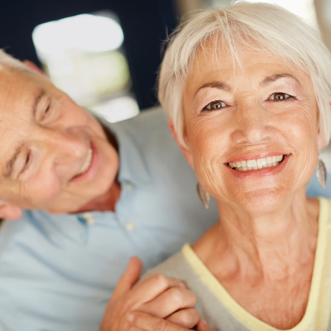 Smiling woman in foreground holding hands with a man leaning in behind her
