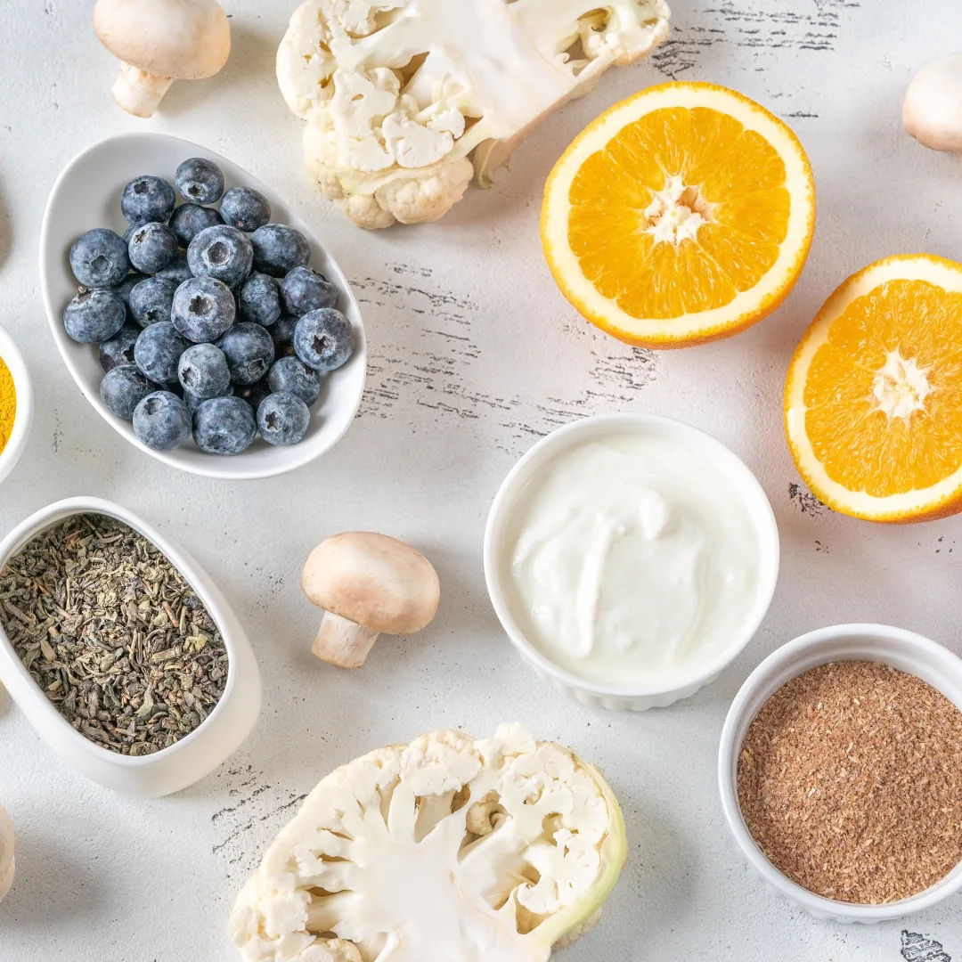 Blueberries, dried herbs, yogurt, halved orange, cauliflower, mushrooms and ground seeds arranged as natural foods and herbs for sleep support