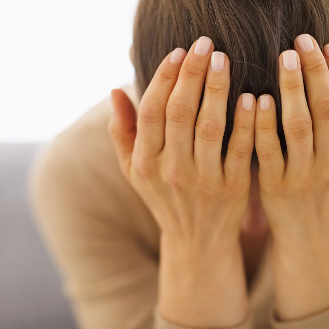 Person with hands covering their face and head bowed
