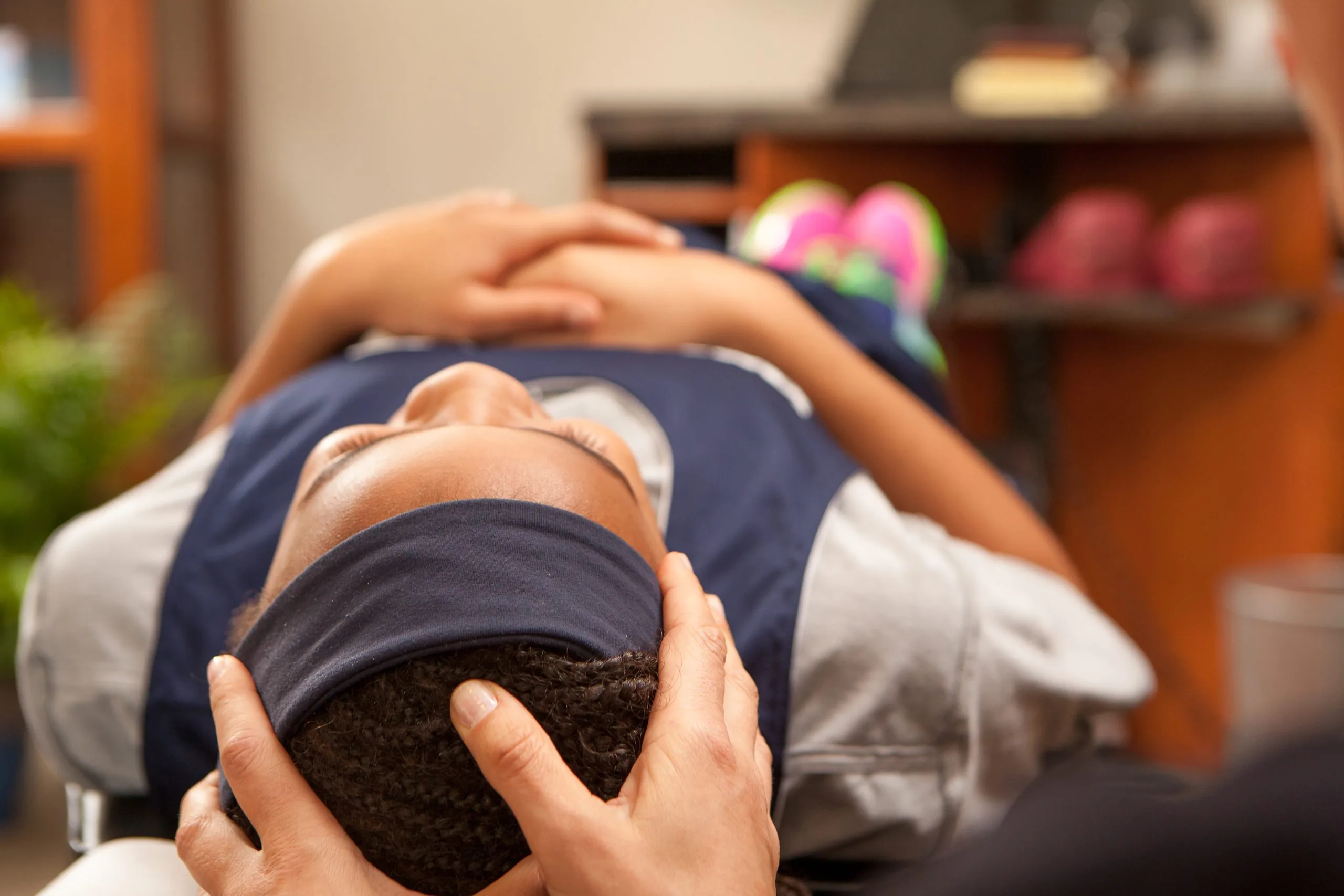 Person lying on an exam table with hands gently supporting their head