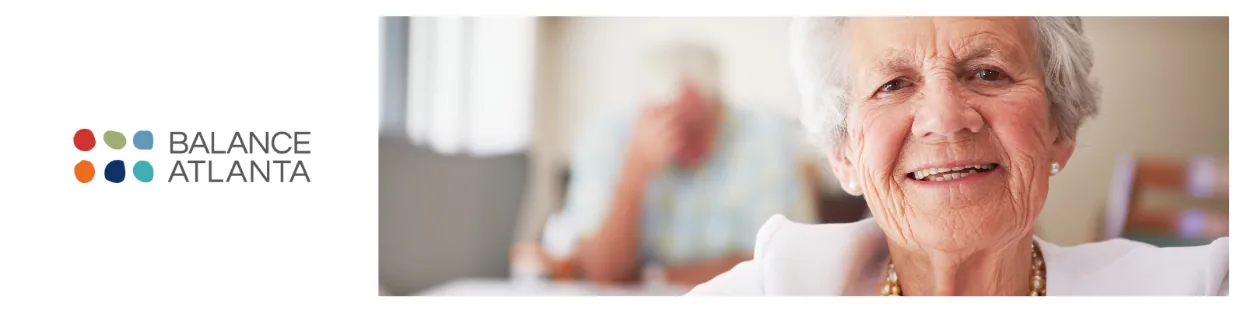 Smiling woman with gray hair in a bright care setting, blurred person in the background, Balance Atlanta logo at left.
