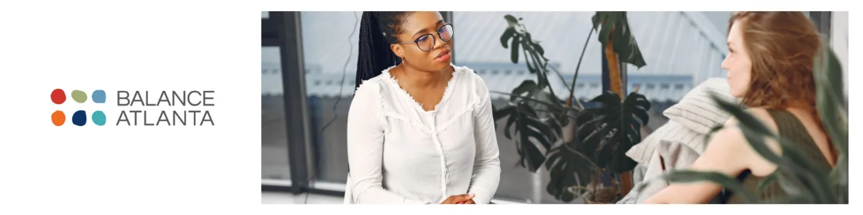 Two people in conversation in an office setting, one wearing glasses and a white blouse; Balance Atlanta logo visible on the left.