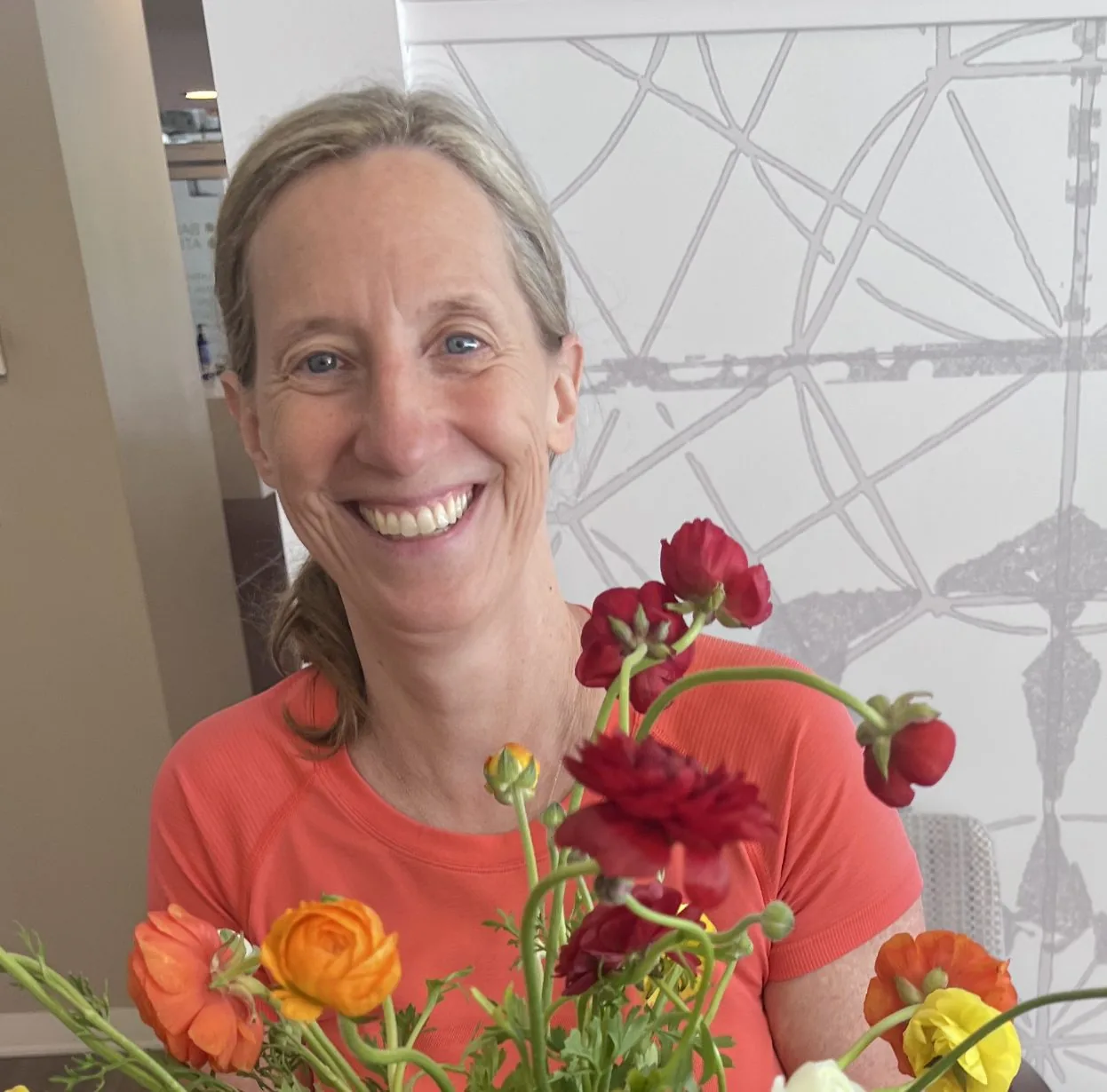 Smiling woman holding a bouquet of red, orange, and yellow flowers